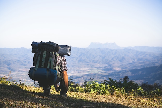 Turista desde la cima de la montaña. rayos de sol. hombre usa mochila grande contra la luz del sol