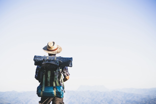 Turista desde la cima de la montaña. rayos de sol. hombre usa mochila grande contra la luz del sol