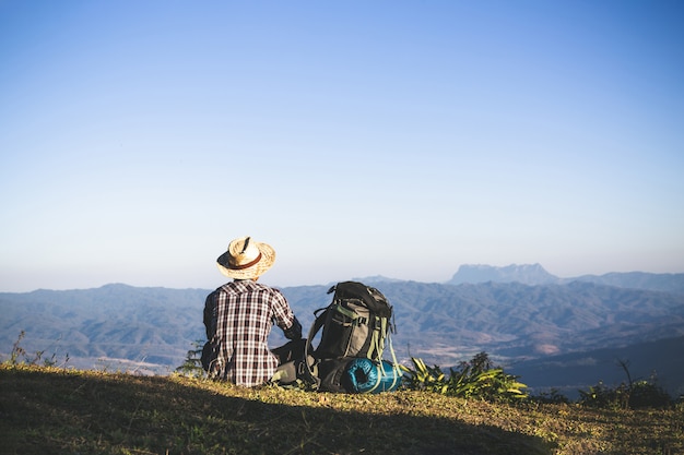 Turista desde la cima de la montaña. rayos de sol. hombre usa mochila grande contra la luz del sol