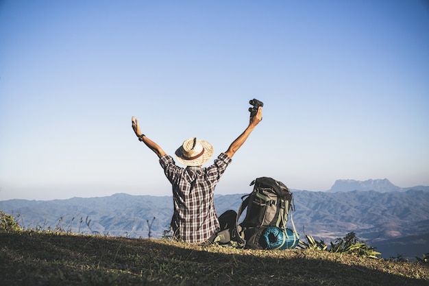 Foto gratuita turista desde la cima de la montaña. rayos de sol. hombre usa mochila grande contra la luz del sol