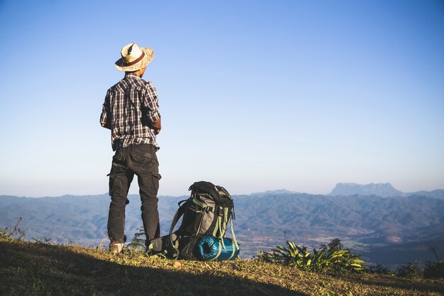 Turista desde la cima de la montaña. rayos de sol. hombre usa mochila grande contra la luz del sol