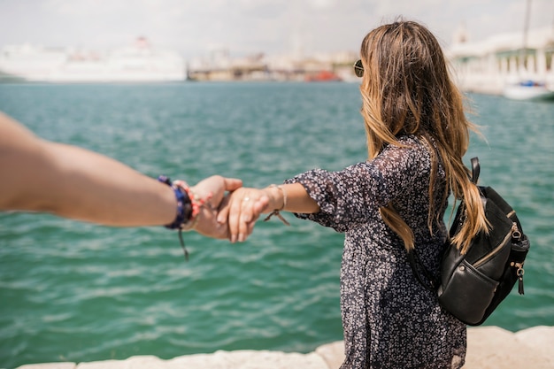 Turista femenina que mira el mar que lleva a cabo la mano de su novio