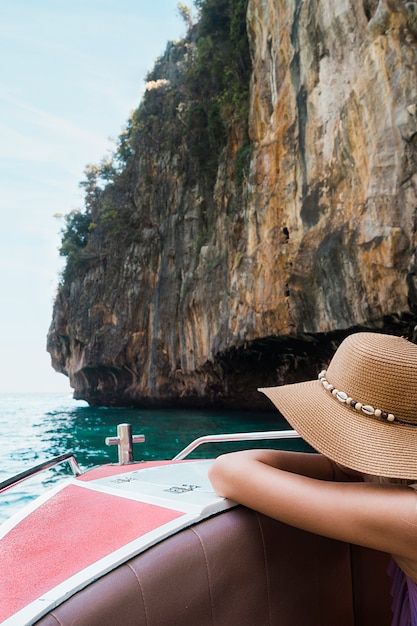 Turista femenino que se inclina en viaje del barco cerca del acantilado