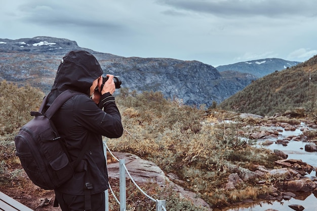 Turista fotógrafo de la naturaleza con tomas de cámara mientras está de pie en la montaña de Noruega.