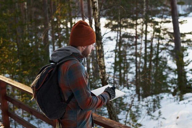 Turista haciendo notas de viaje en el bosque o dibujando bocetos de naturaleza ecológica