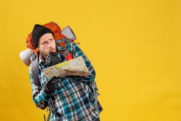 Turista joven asustado con guantes de cuero y mochila con mapa