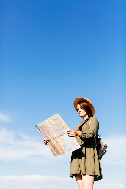 Turista con mapa sobre fondo de cielo soleado