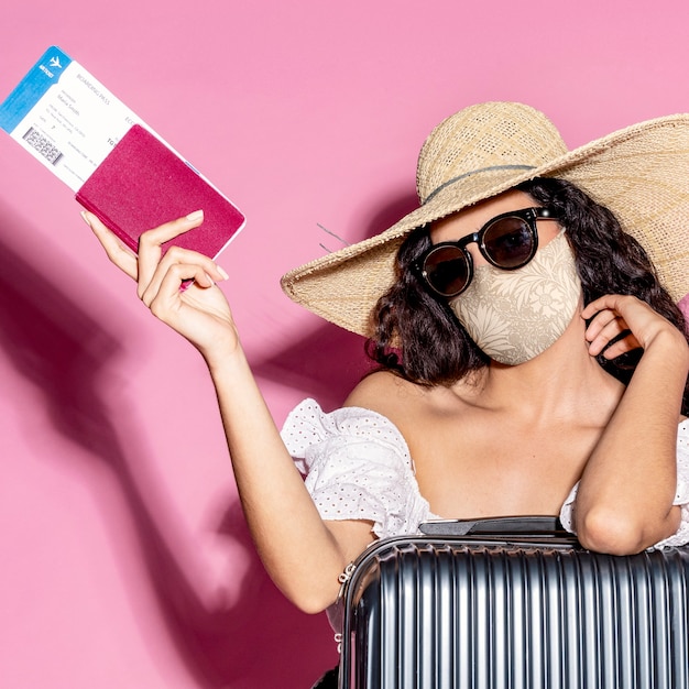 Turista en mascarilla con pasaporte y equipaje.