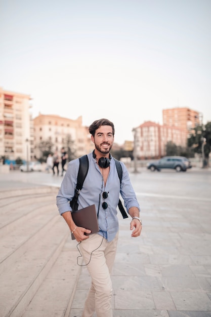 Turista masculino con la computadora portátil caminando por la escalera