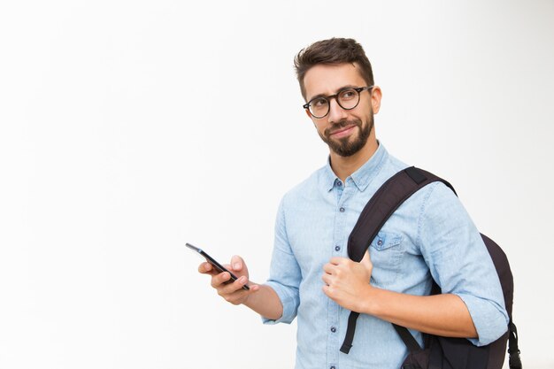 Turista masculino positivo con mochila mediante teléfono móvil