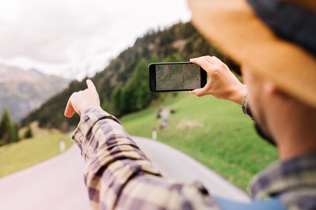 Turista masculino con sombrero marrón claro yendo a los Alpes y usando el navegador para evitar perderse