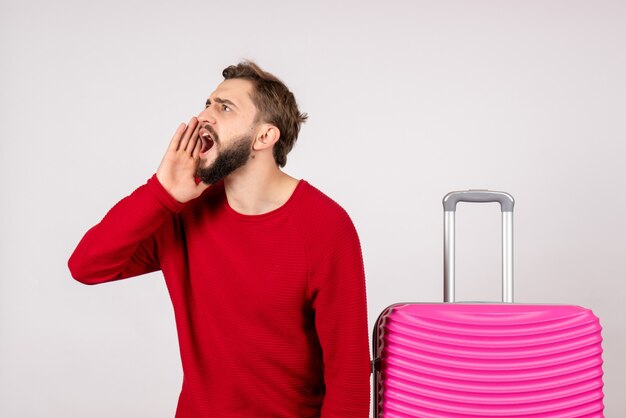 Turista masculino de vista frontal con bolsa rosa sobre pared blanca