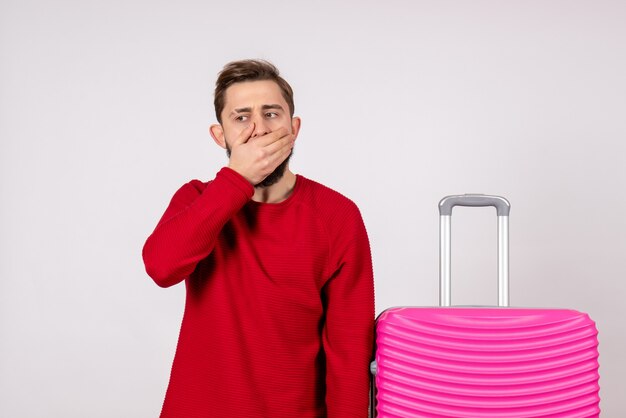 Turista masculino de vista frontal con bolsa rosa sobre pared blanca