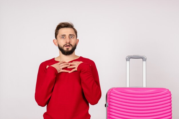 Turista masculino de vista frontal con bolsa rosa sobre pared blanca