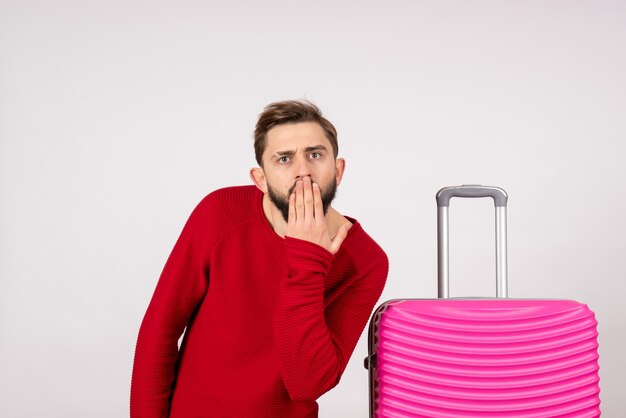 Turista masculino de vista frontal con bolsa rosa sobre pared blanca