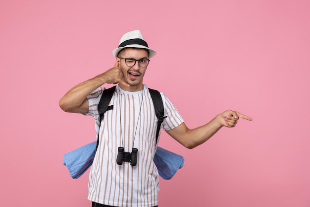 Turista masculino de vista frontal posando con mochila en turista de emociones de color de pared rosa