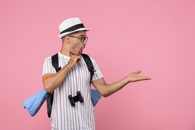 Turista masculino de la vista frontal que presenta con la mochila en color rosado del turista de la emoción del escritorio