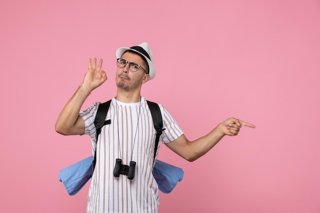 Turista masculino de la vista frontal que presenta con la mochila en el turista rosado de la emoción del color del escritorio