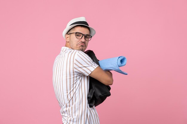 Turista masculino de la vista frontal que sostiene su bolso en turista del color de la emoción de la pared rosada