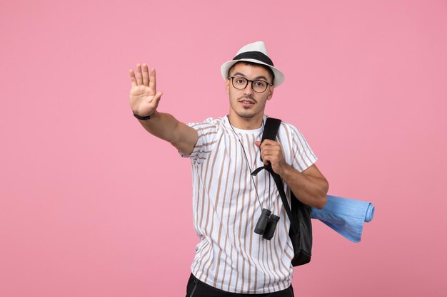 Turista masculino de la vista frontal con su mochila en las emociones turísticas del color de la pared rosada