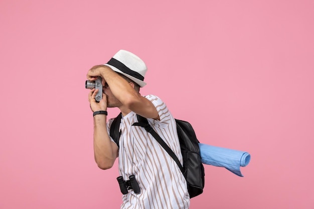 Turista masculino de la vista frontal tomando fotos con la cámara en el color rosado del turista de la emoción del piso