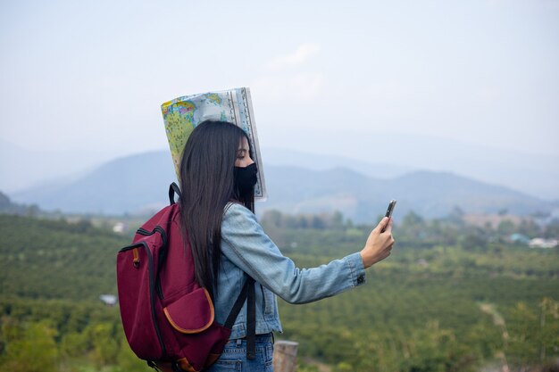 Turista mujer asiática vistiendo mascarilla mirando teléfono