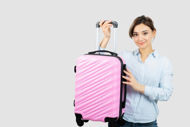 Turista de mujer de pie y sosteniendo una maleta de viaje rosa. Foto de alta calidad