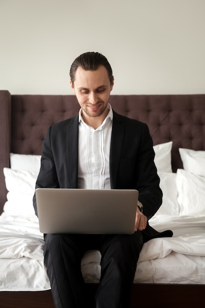 Turista de negocios trabajando en la computadora portátil en la habitación del hotel