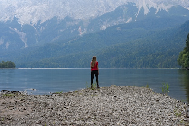 Turista observando la vista de colinas y montañas cubiertas de vegetación cerca de una aldea en Austria