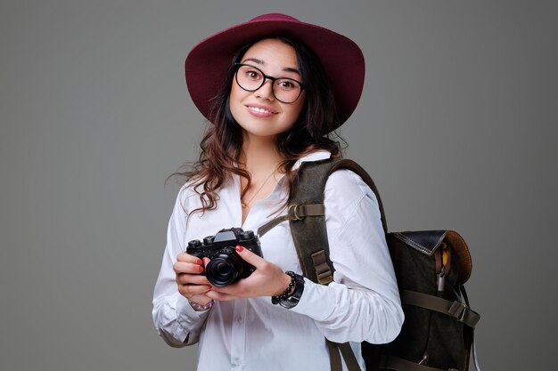 Turista positiva con cámara fotográfica y mochila de viaje.