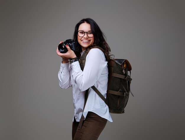 Turista positiva con cámara fotográfica y mochila de viaje.