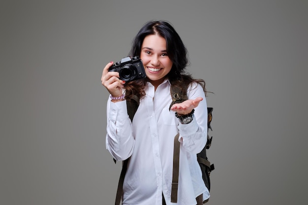 Turista positiva con cámara fotográfica y mochila de viaje.