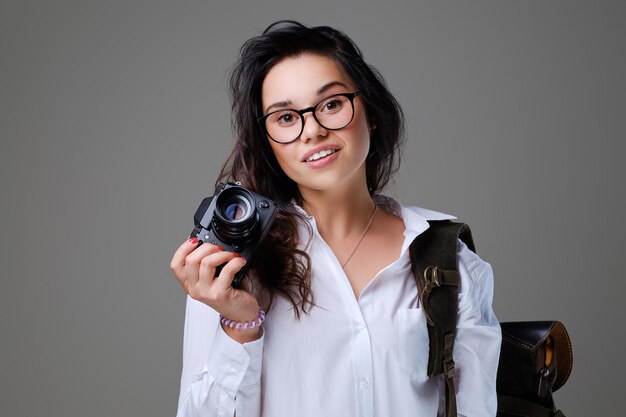 Turista positiva con cámara fotográfica y mochila de viaje.