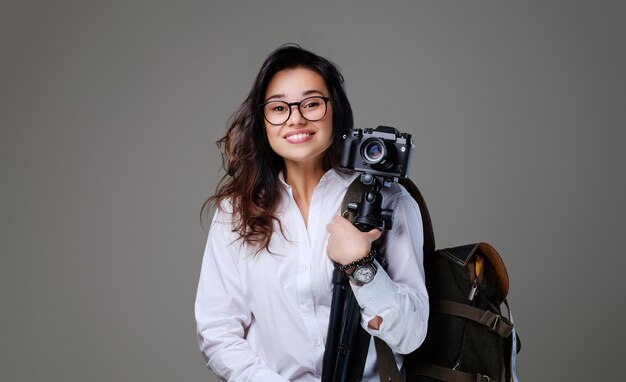 Turista positiva con cámara fotográfica y mochila de viaje.