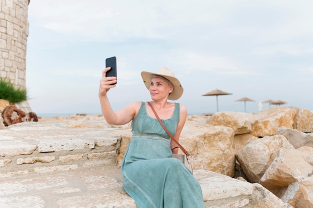 Turista senior mujer con sombrero de playa tomando selfie