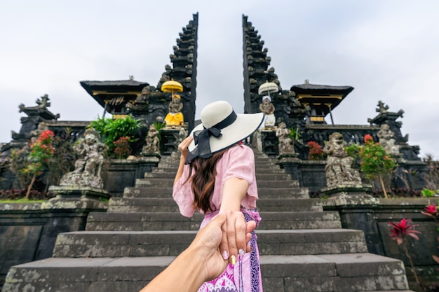 Turista sosteniendo la mano del hombre y llevándolo al templo Besakih en Bali, Indonesia