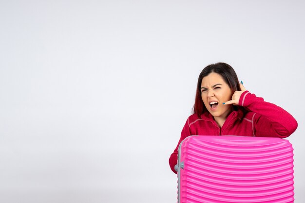 Turista de vista frontal con bolsa rosa sobre pared blanca