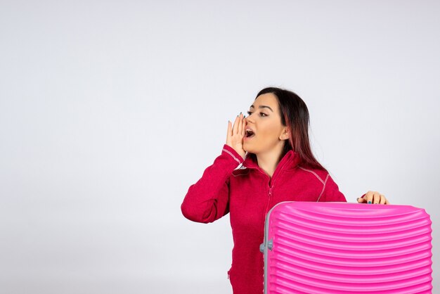 Turista de vista frontal con bolsa rosa sobre pared blanca