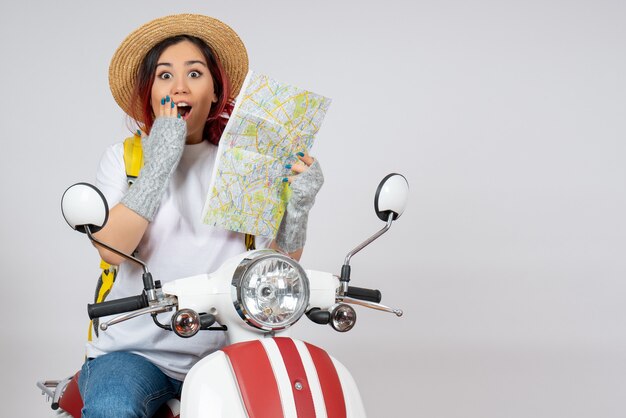 Turista de vista frontal sentada en motocicleta con mapa pared blanca