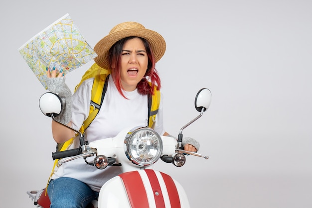 Turista de vista frontal sentada en motocicleta con mapa pared blanca