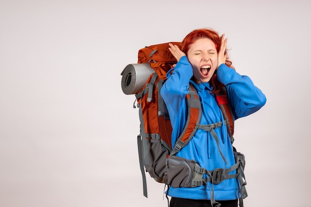 Turista de vista frontal en viaje de montaña con mochila cubriendo sus oídos