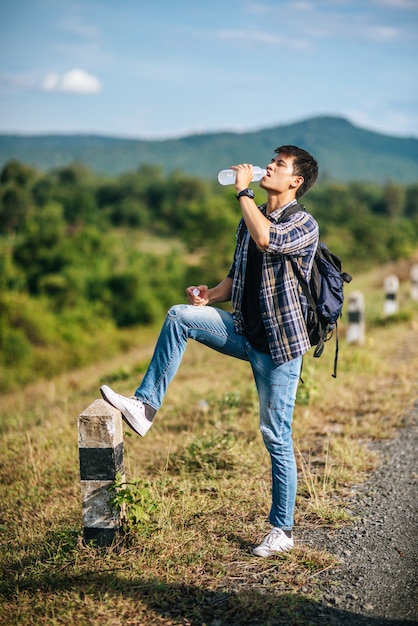 Los turistas hombres beben agua y los pies pisan kilómetros.