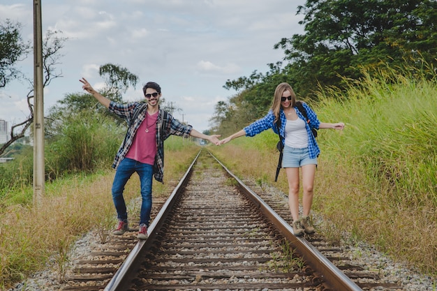 Turistas jóvenes tomándose las manos en vías de tren