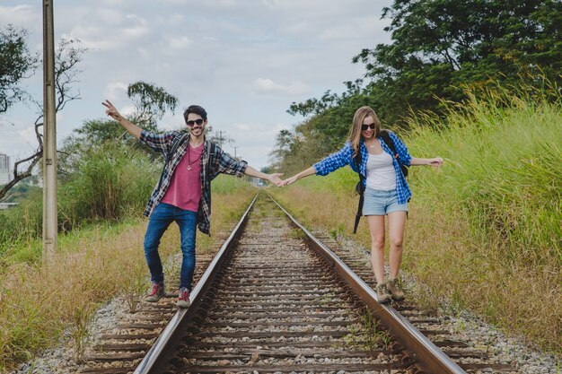 Turistas jóvenes tomándose las manos en vías de tren