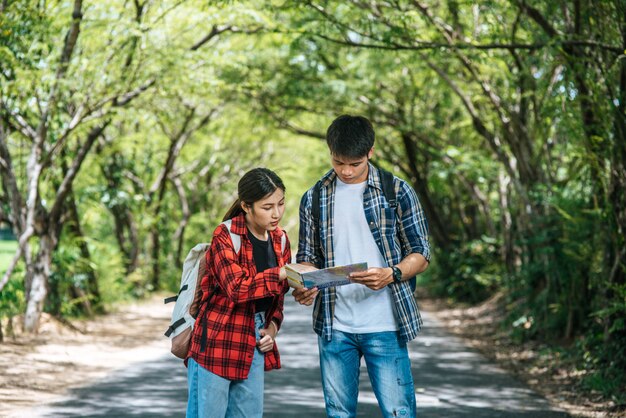 Los turistas masculinos y femeninos miran el mapa en el camino.