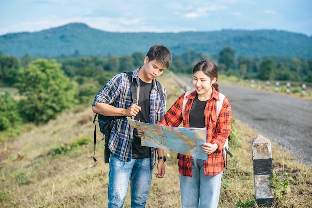 Turistas masculinos y femeninos de pie miran el mapa de carretera.