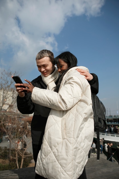 Turistas masculinos y femeninos revisando su teléfono inteligente al aire libre