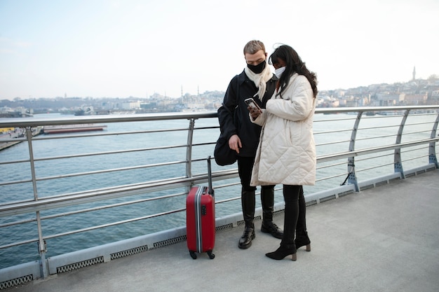 Turistas masculinos y femeninos revisando su teléfono inteligente al aire libre