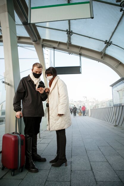 Turistas masculinos y femeninos revisando su teléfono inteligente al aire libre