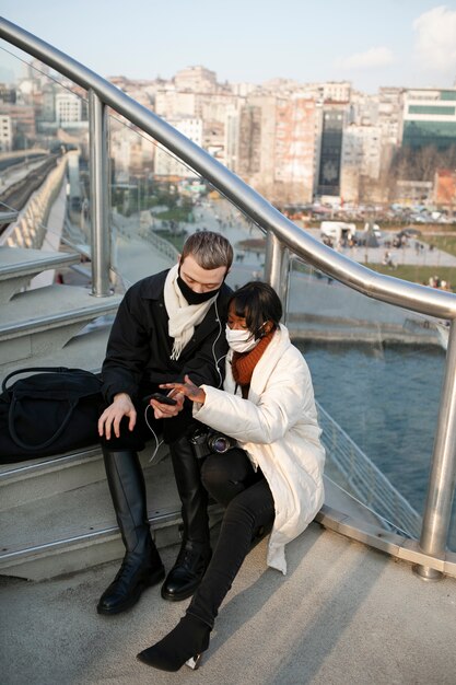 Turistas masculinos y femeninos revisando su teléfono inteligente al aire libre